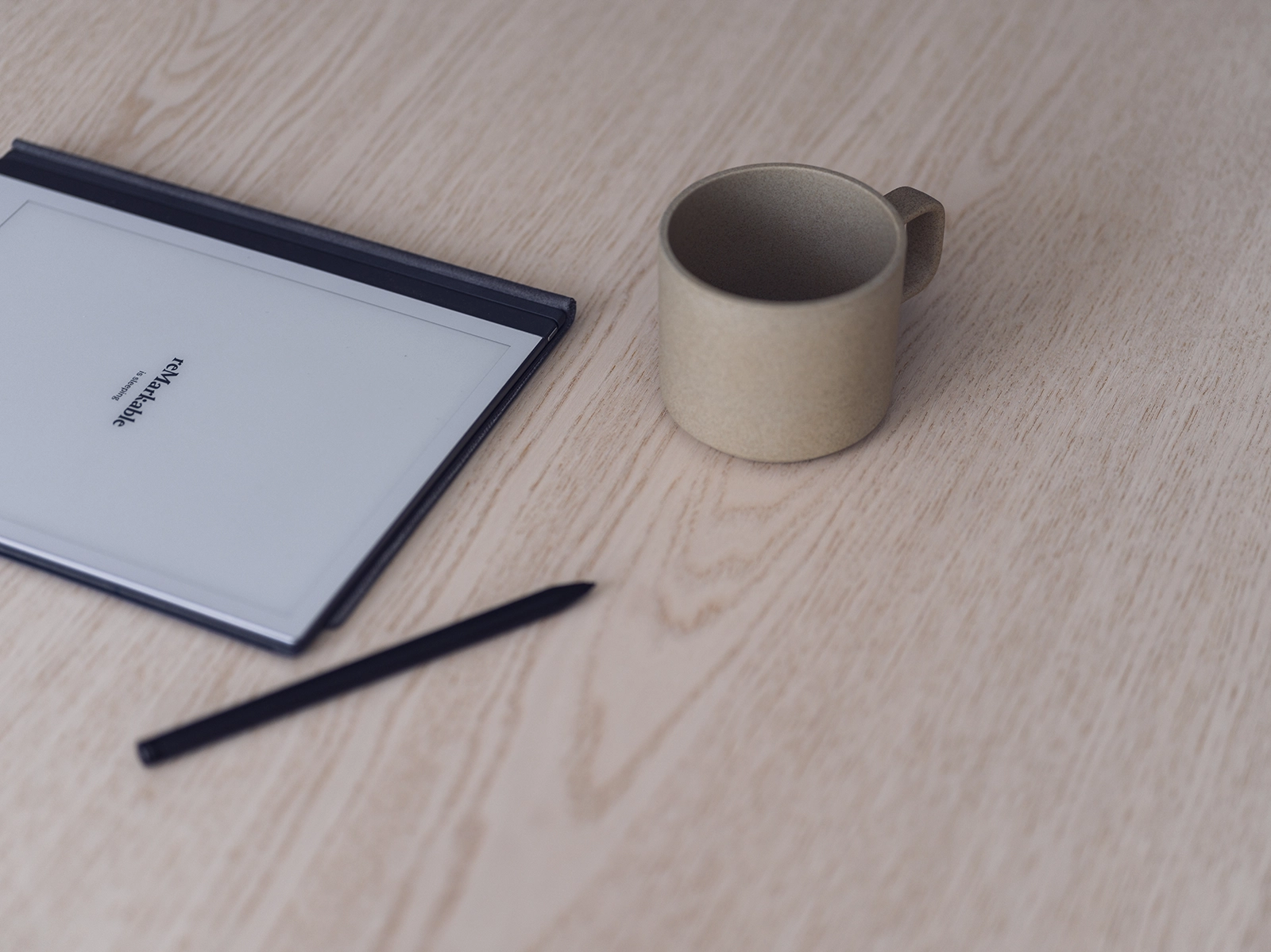 Digital skrivplatta på träbord bredvid beige kaffekopp.